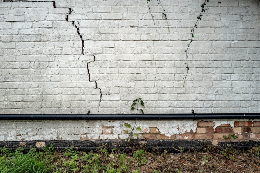 Lines of cracks in the side of a white brick house